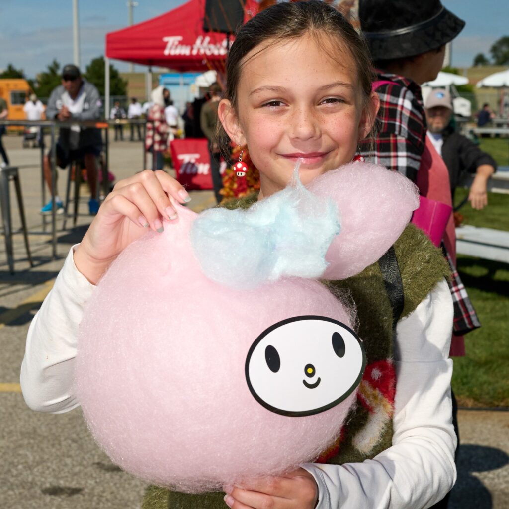 Child holding pink cotton candy shaped like a character